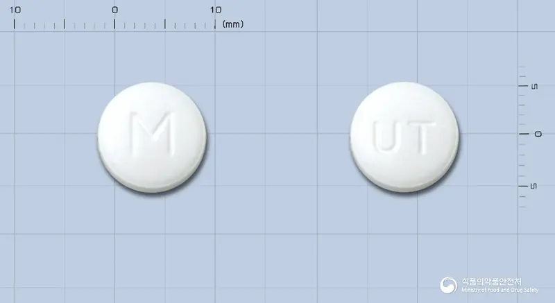 한국유나이티드염산메트포르민정(수출명: Glumyomin Tabs., Glyzen Tabs., Metmentab., Diazen Tabs.) 앞뒤 사진 (흰색 원형, 각인 M / UT)