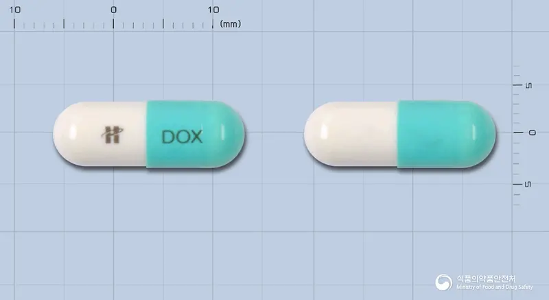 휴온스독시사이클린하이클레이트캡슐100mg(수출명:독시메디코캡슐,테라독신캡슐,DOXYCYCLINE-ASTERIA 100mg Cap.)(수출용) 앞뒤 사진 (파란색 캡슐, 각인 DOX)