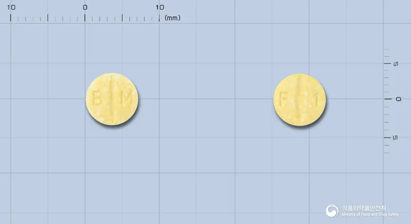 딜라트렌정6.25mg(카르베딜롤) 앞뒤 사진 (노란색 원형, 각인 B M / F 1)