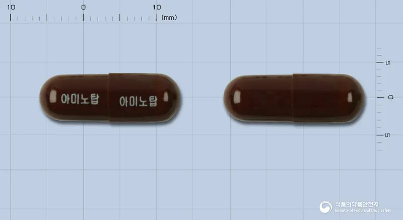 아미노탑캡슐(수출용) 앞뒤 사진 (갈색 캡슐, 각인 아미노탑 아미노탑)