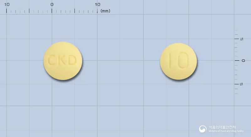 뉴로페질정10밀리그램(도네페질염산염일수화물) 앞뒤 사진 (노란색 원형, 각인 CKD / 10)