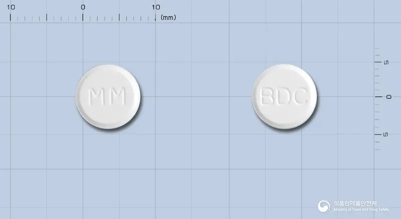 비디셀정(비페닐디메틸디카르복실레이트) 앞뒤 사진 (흰색 원형, 각인 MM / BDC)