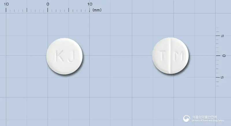 트로피움정(브롬화시메트로피움) 앞뒤 사진 (흰색 원형, 각인 KJ / T M)