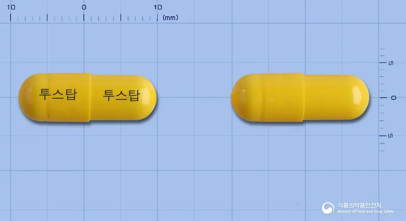 투스탑캡슐 앞뒤 사진 (노란색 캡슐, 각인 투스탑 투스탑)