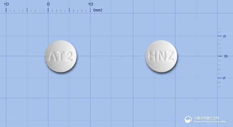 휴니즈아토르바스타틴칼슘정20mg(아토르바스타틴칼슘삼수화물) 앞뒤 사진 (흰색 원형, 각인 AT2 / HNZ)