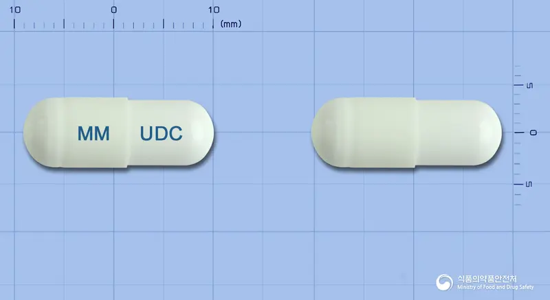유앤씨캡슐 앞뒤 사진 (흰색 캡슐, 각인 MM UDC)